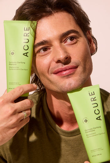 Man holding Acure Curiously Clarifying Shampoo and conditioner